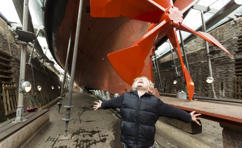 Boy stood next to ship's propeller
